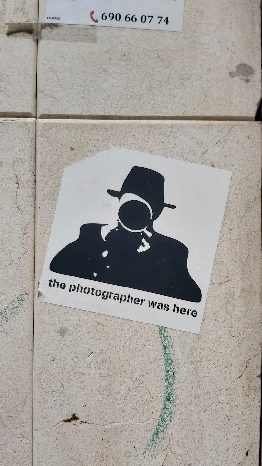 Pegatina 'the photographer was here' sobre un muro de piedra