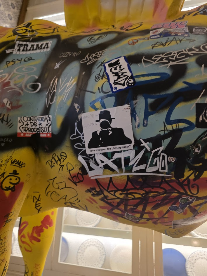 Pegatina del fotógrafo entre grafitis sobre una escultura
