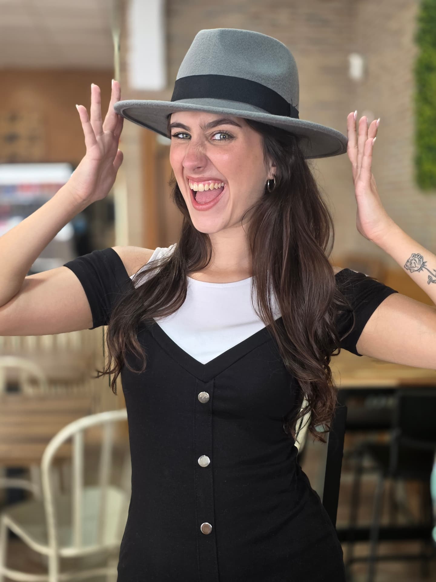 Camila bromeando con el sombrero entre tomas en la cafetería